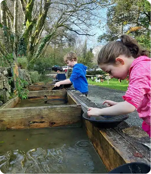 Children panning (sifting) material in water to find small minerals or gems as part of that experience at Glengowla Mines & Family Farm Experience